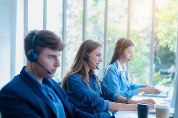 Portrait of call center worker accompanied by team. They helping information to customer and...
