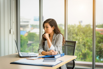 A Beautiful Confident asian young business woman working with laptop computer and checking document file on desk for successful business at office work place.