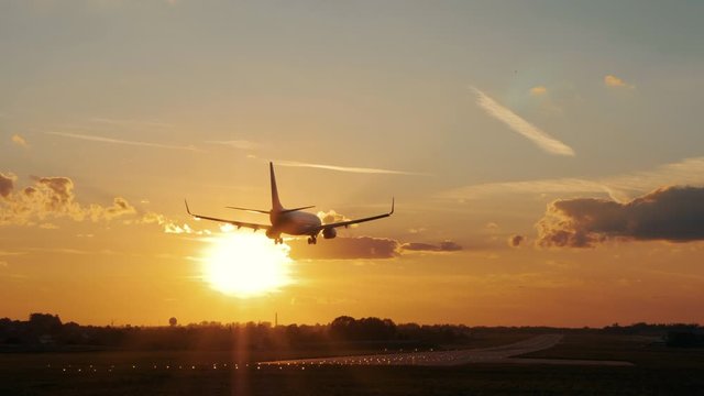 Landing airplane in airport runway at dusk sunset. Dynamic close up shot filmed in 4k UHD 2160p