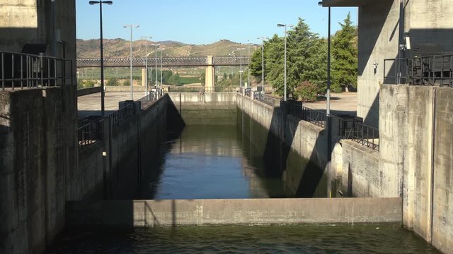 Closer view of Barragem do Pocinho dam as a river cruise boat on the Douro waits as the lock fills with water ready for the descent