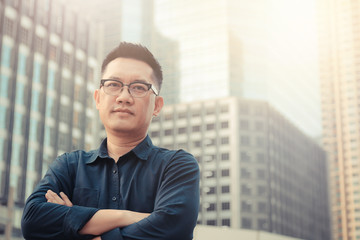 Confident male business executive  with arms crossed standing in front of office building