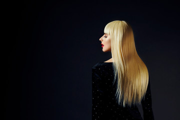 Profile portrait of a beautiful platinum blonde model with healthy, shiny  hair isolated on black studio background