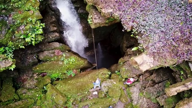 Men ready to drop into a hole with water cascading inside