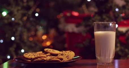 Santa eating cookies and drinking milk, then stuffing his face in front of christmas tree - shot on RED - Powered by Adobe