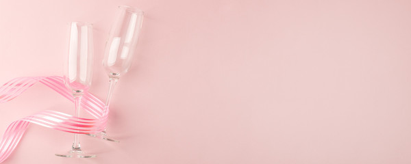 Valentines day greeting card. Empty Wine glasses for wine and ribbon on a soft light pink background. Flat lay, top view, copy space, minimal february  romance concept, banner