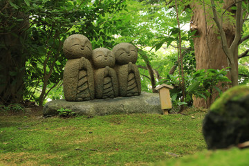 Small statues of baby buddhas surrounded by fresh green at the Hase-Dera temple in Kamakura, Japan