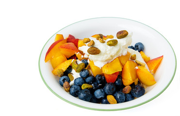 Top view of a bowl of fruit and pistachio nuts over greek yogurt  isolated on white