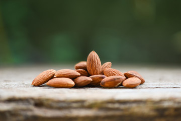 Almonds on wooden table and nature background / Close up almond nuts natural protein food and for...