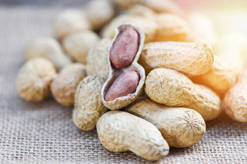 Roasted peanuts on a wooden bowl and sack background - Peanut in shells for food or snack