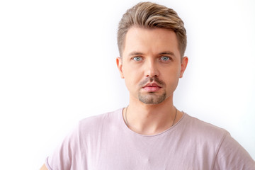 Fototapeta premium Stylish young blond with a beard, fashionable European hipster, in a pink T-shirt on a white background, closeup portrait
