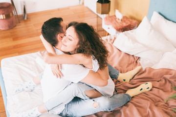 Fototapeta premium Happy young couple tenderly hugging on the bed in the bedroom, romantic time together concept.