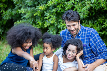 Young mixed race family playing in garden, father and daughter play game on holiday