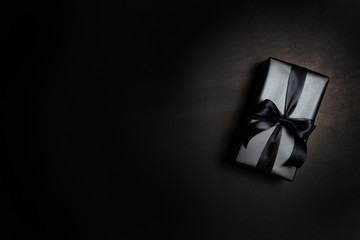 Top view of black gift box with black ribbons isolated on black background.