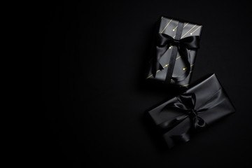 Top view of black gift box with black ribbons isolated on black background.
