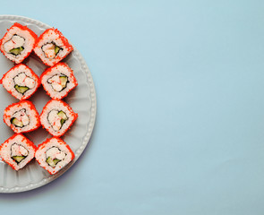 Japanese rolls on grey plate on blue background.