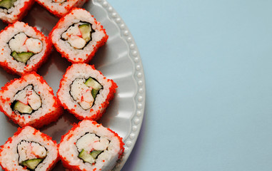 Japanese rolls on grey plate on blue background.