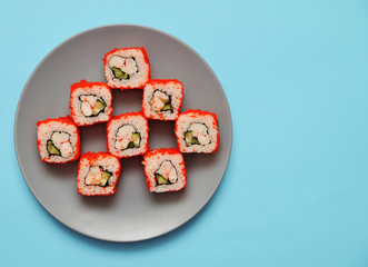 Japanese rolls on grey plate on blue background.