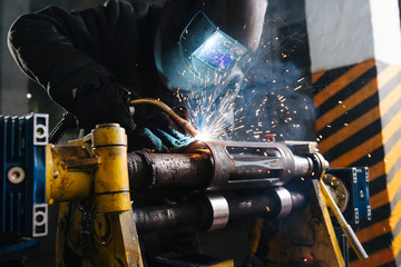 Close up of a craftsman welding metal piece, fixed with industrial clamp.