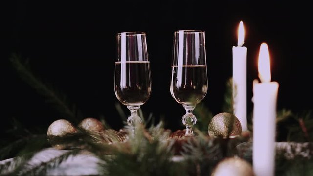 Female hand takes a glass with champagne christmas decor background and candles