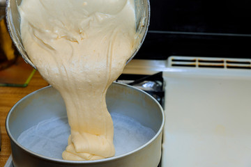Pouring cake dough into round baking pan.