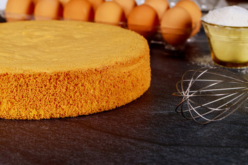 Soft sponge cake with ingredients: brown eggs, flour and whisk. Bakery concept.