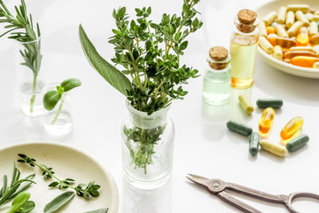Naklejka na ściany i meble Healing herbs in glasses and medicine on white background