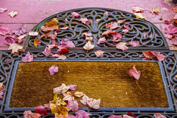 Front door mat with colorful fall leaves - focus on foreground.