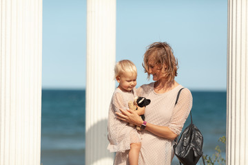 Pretty happy mom and little daughter on a walk near the sea