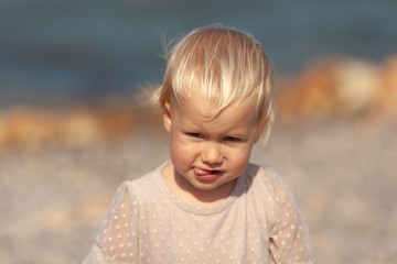 Portrait of a pretty little girl on the background of the sea, the baby walks on the shore