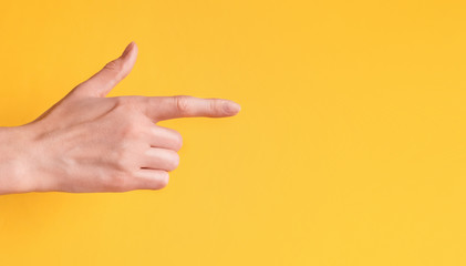 Young woman showing arrow hand gesture on color background. Space for text