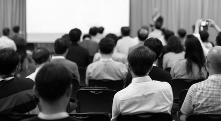 Seminar presenter at corporate conference giving speech. Speaker giving lecture to business audience. Executive manager leading discussion in hall during company training event. 