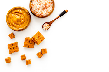 Trendy sweets - salted caramel - melted and cubes on white background top view copy space