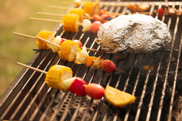 Skewers of delicious corn onions, red peppers and colorful tomatoes for a healthy vegetarian meal, complete with barbecue on a fire-cut stove.soft focus.shallow focus effect.