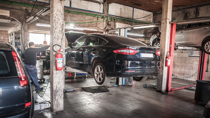 Car mechanic working in a repair garage with hydraulic car lift