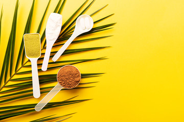 Trendy collagen powder types on yellow background: plain, matcha, chocolate, pills. Flat lay, top...