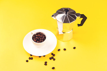 Coffee maker and espresso cup on yellow background. Coffee love concept.