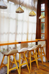 Beautiful and bright interior with brown wooden bar stools and simple triangle lamp.       
