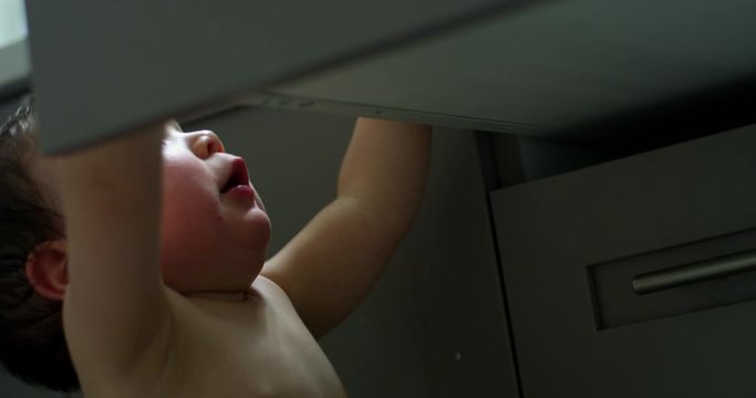 Baby boy opens cabinet drawer in bathroom - exploring troublemaker