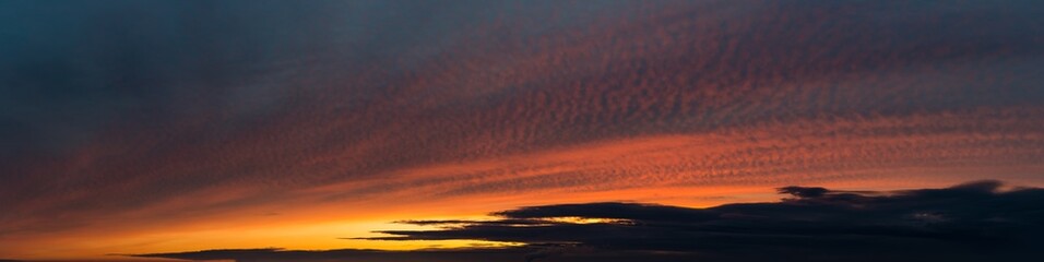 Fantastic dark thunderclouds at sunrise, wide panorama