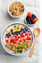 Yogurt bowl with berries, granola and fruit on linen textile backround. Table top view. Healthy vegetarian food, clean eating concept