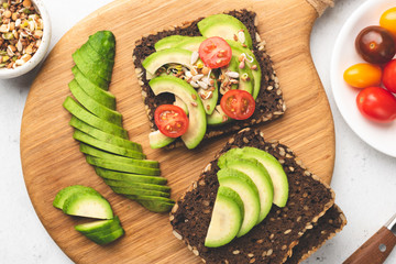 Rye bread toast with avocado, tomato, sprouts. Healthy food, vegan vegetarian snack, weight loss concept. Table top view