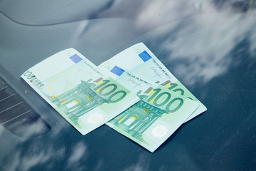 Euro banknotes on the dashboard and their reflection in the windshield inside of a car