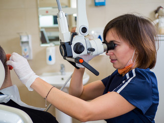 Male patient at the reception in the ENT clinic. Female doctor examines an ear through a special...