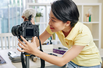 Smiling pretty young woman installing digital camera and microphone