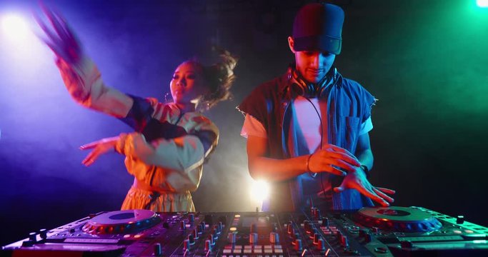 A dj couple is performing together in a nightclub, dancing at mixer controller, rocking the party up - nightlife concept 4k footage