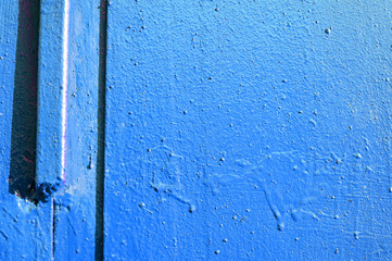 Old door blue color close-up lit by the bright sun. Abstract background