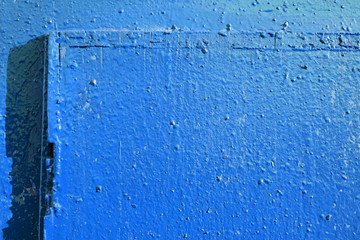 Old door blue color close-up lit by the bright sun. Abstract background