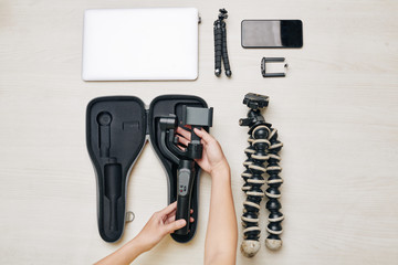Obraz premium Hands of woman packing video production equipment for shooting new blog