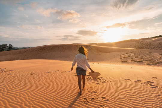 Young woman traveler looking sunset at red sand dunes in Vietnam, Travel lifestyle concept