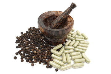 closeup the black pepper in Wooden mortar on white background , selective focus. Herbal Medicines.